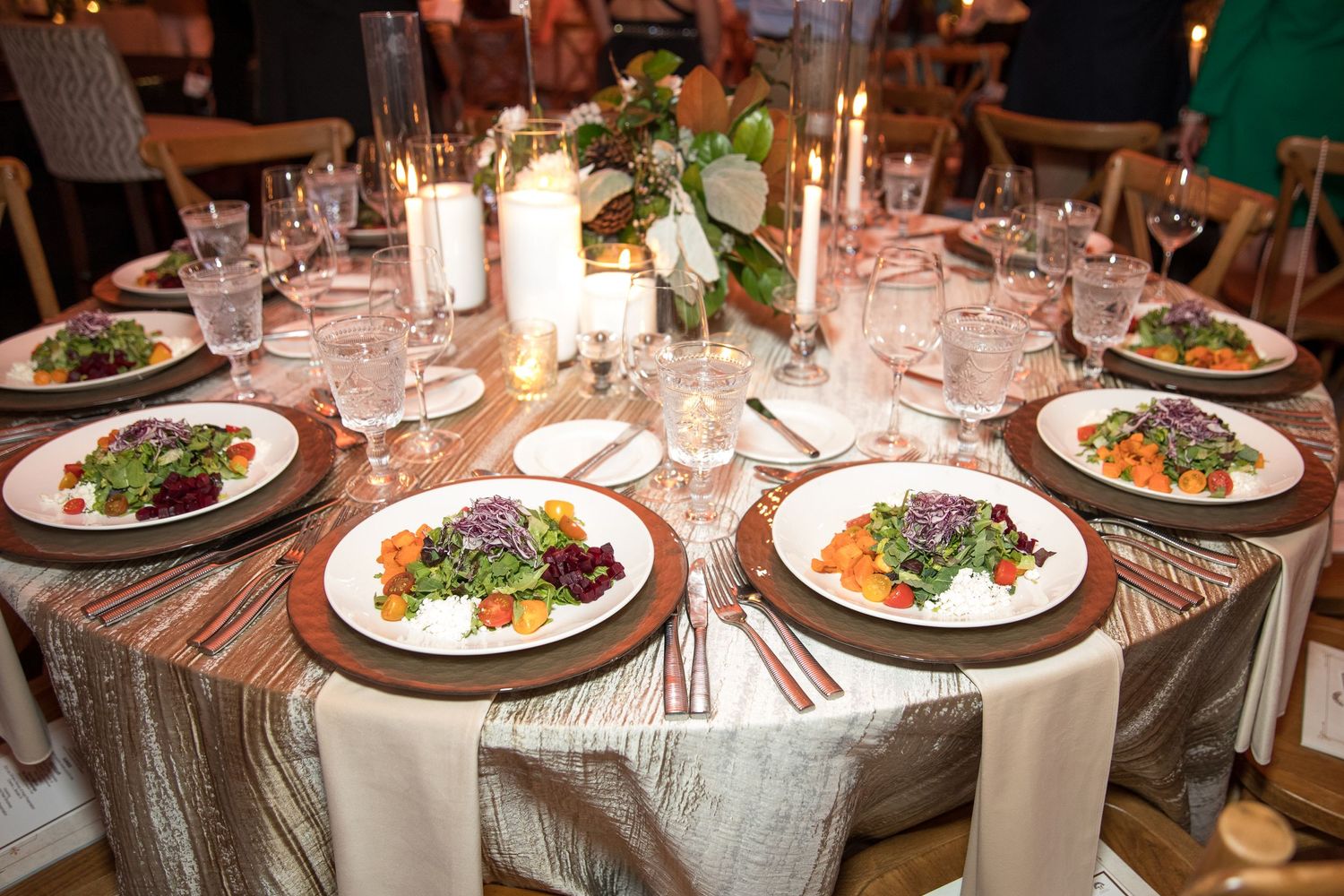 Elegant table setting with plated meals, candles and floral centerpiece.