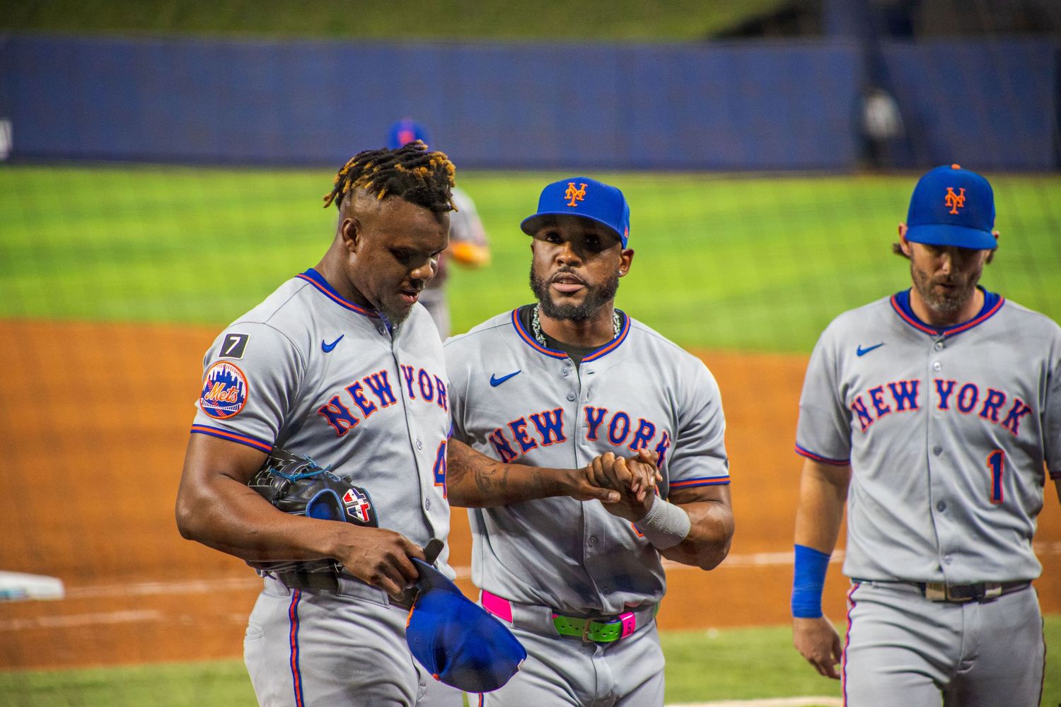 Baseball players in gray uniforms gather on the field during a game.