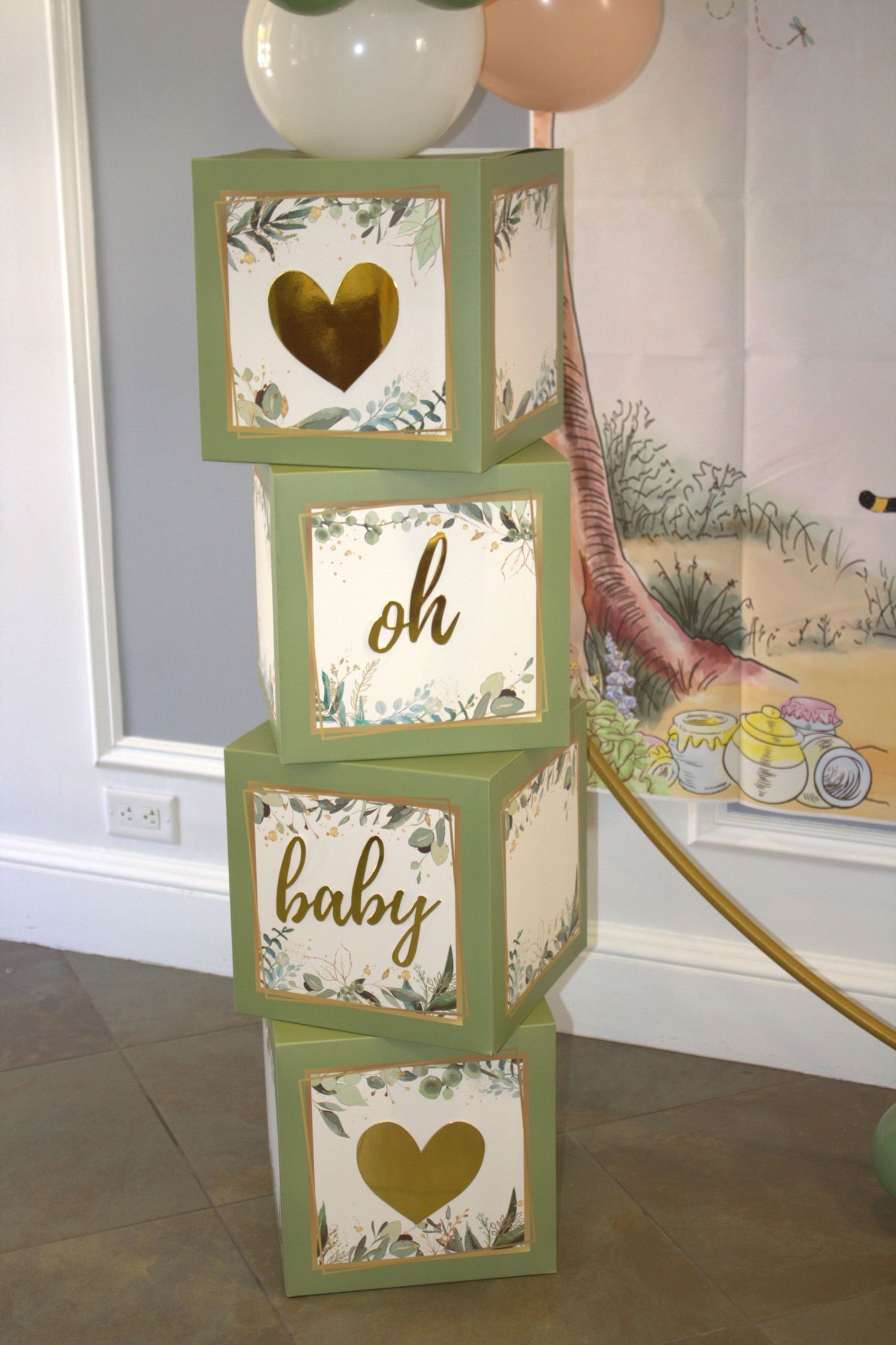 Decorative green baby shower blocks stacked vertically with heart and floral designs.