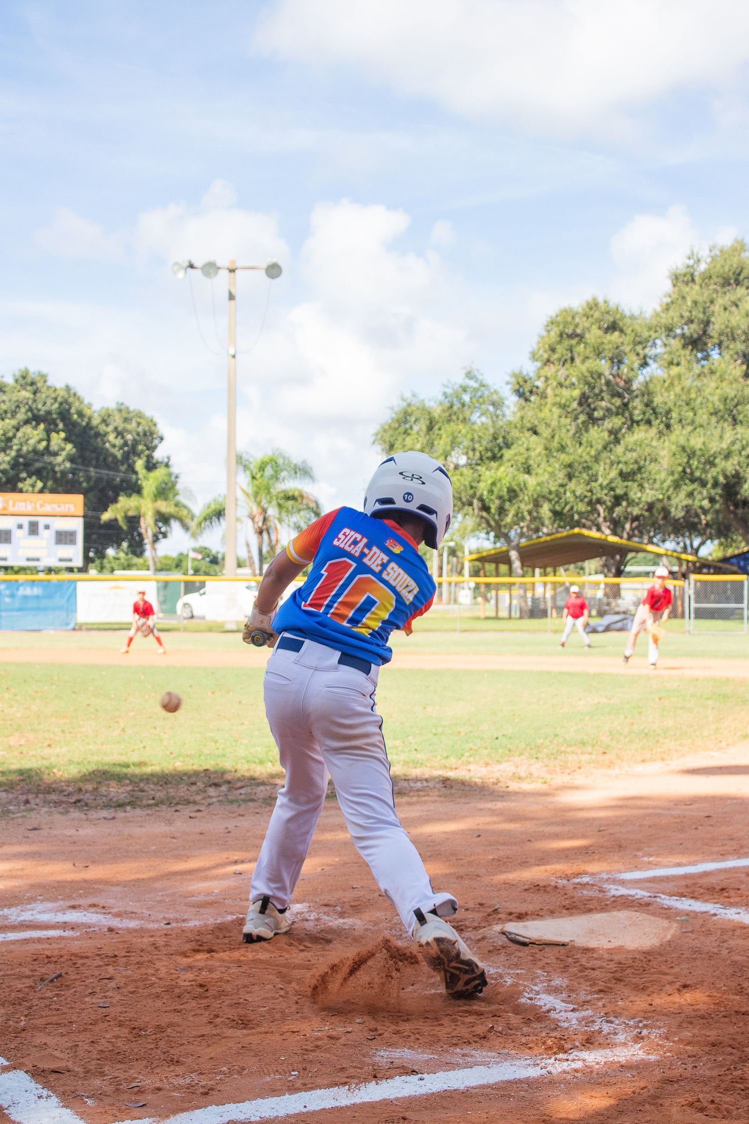 A baseball player in a blue jersey swings the bat at home plate during a game.