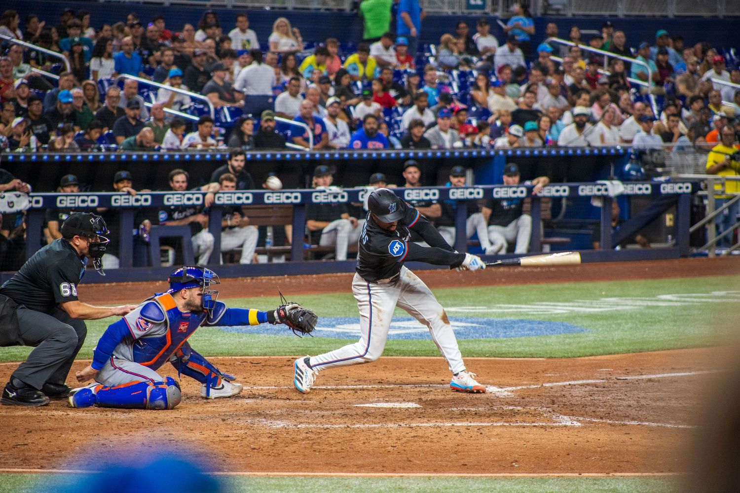 Baseball player slides into home plate during intense MLB game action at a stadium.