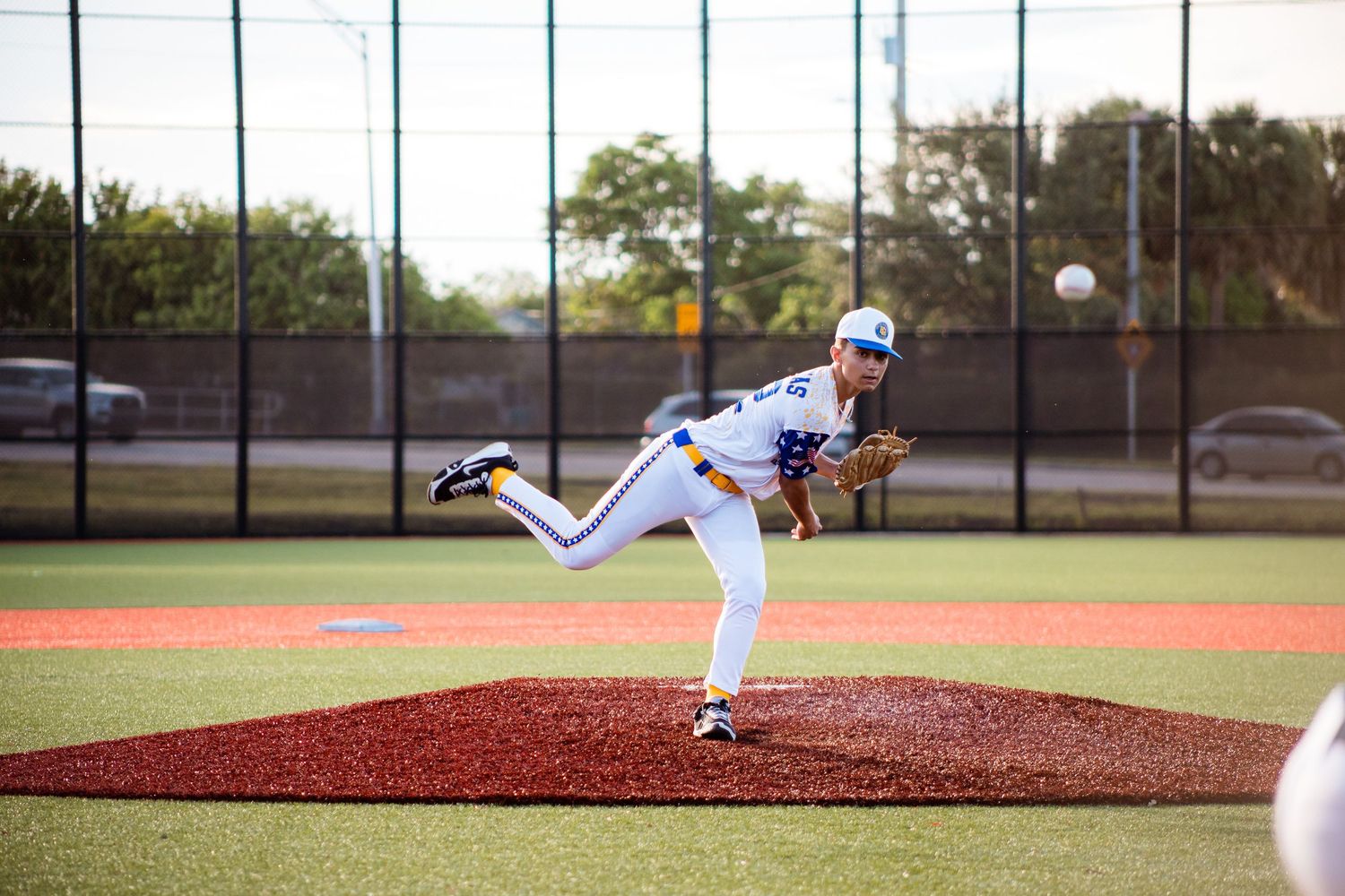 Baseball pitcher in blue uniform follows through on delivery from pitching mound during game.