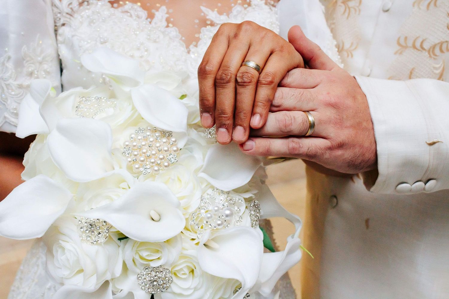 Close-up of white peonies and rose bouquet with berries being arranged by hands wearing gloves.