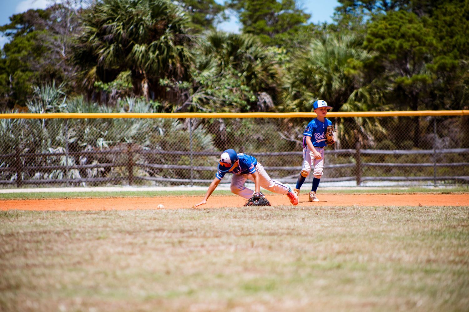 Baseball field with players spread across the diamond during gameplay under blue skies.