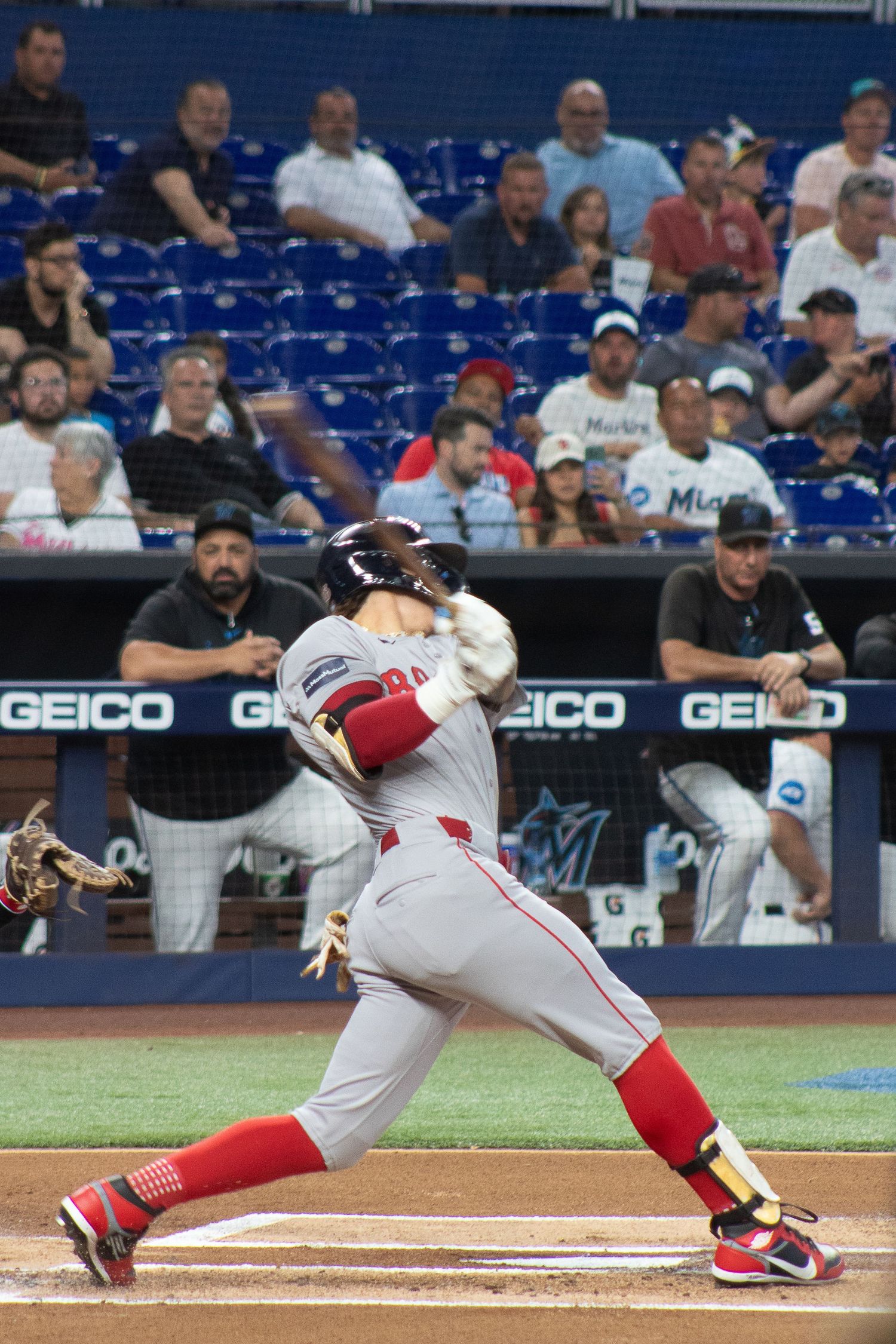 A baseball player in a red and white uniform swings the bat during a game.