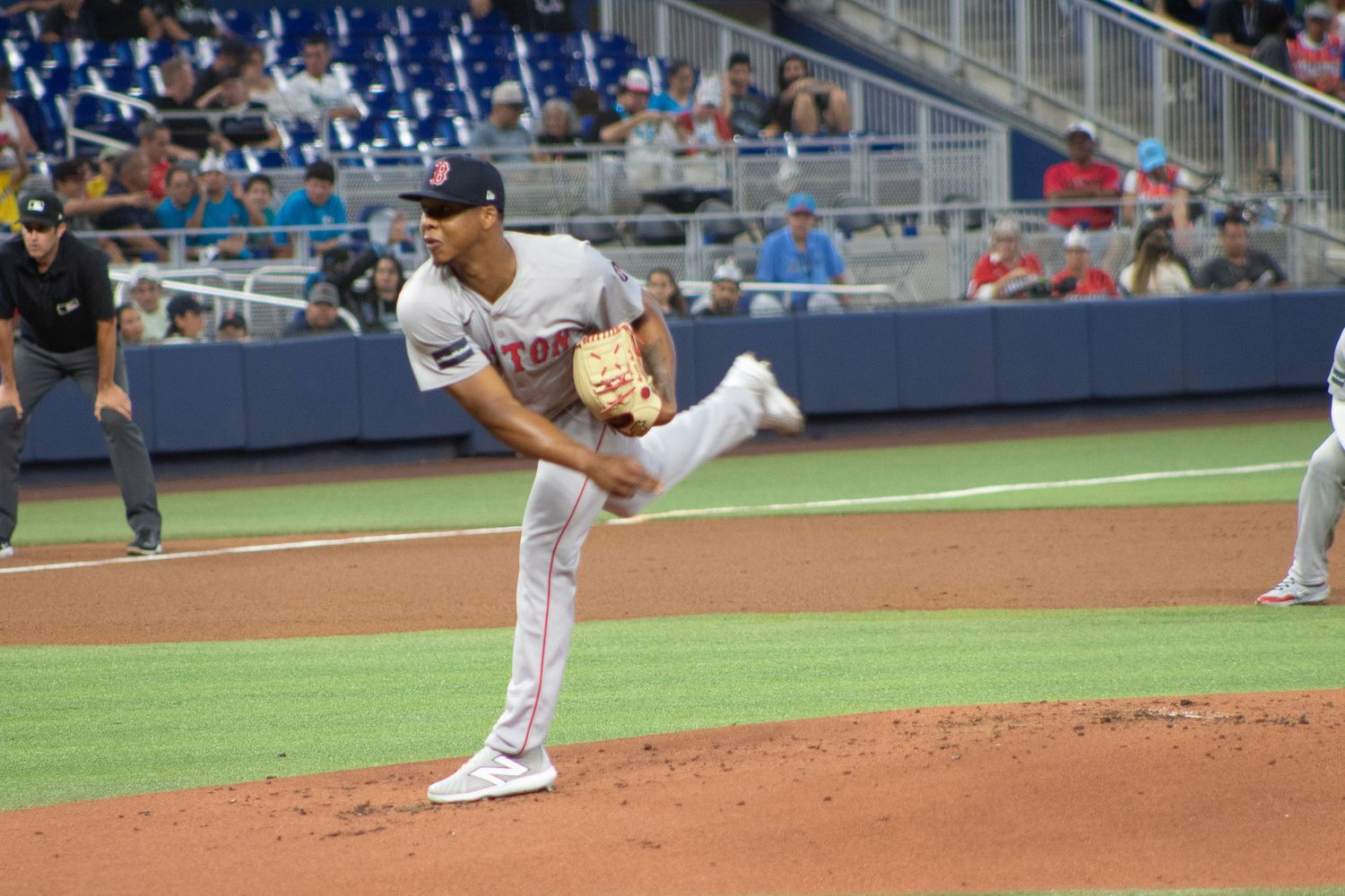 A baseball pitcher in mid-delivery motion on the mound during a game.