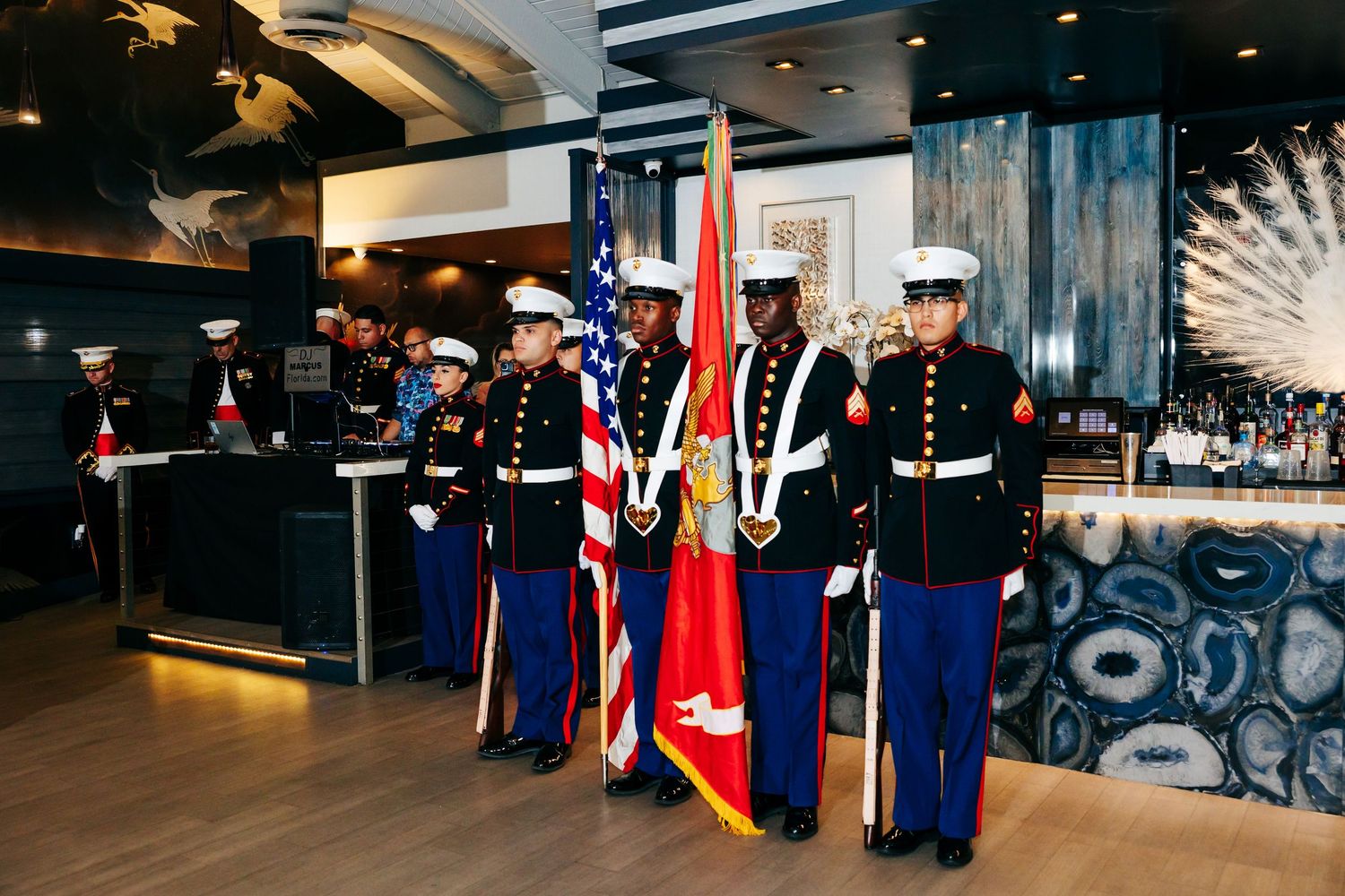 Marines in dress uniforms stand at attention during a ceremonial event in a modern venue.