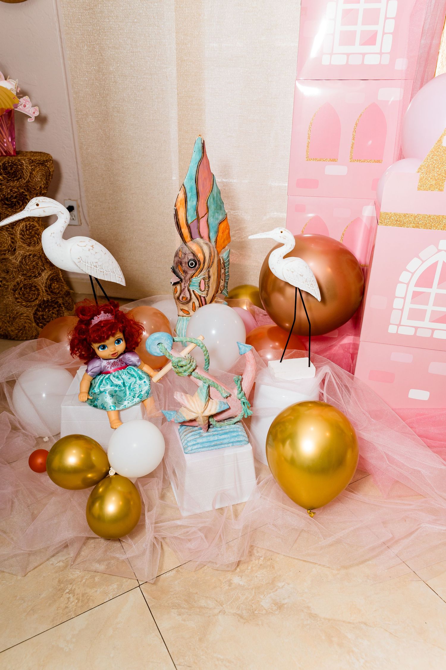 Princess party decorations with white cranes, balloons, and a pink castle backdrop.