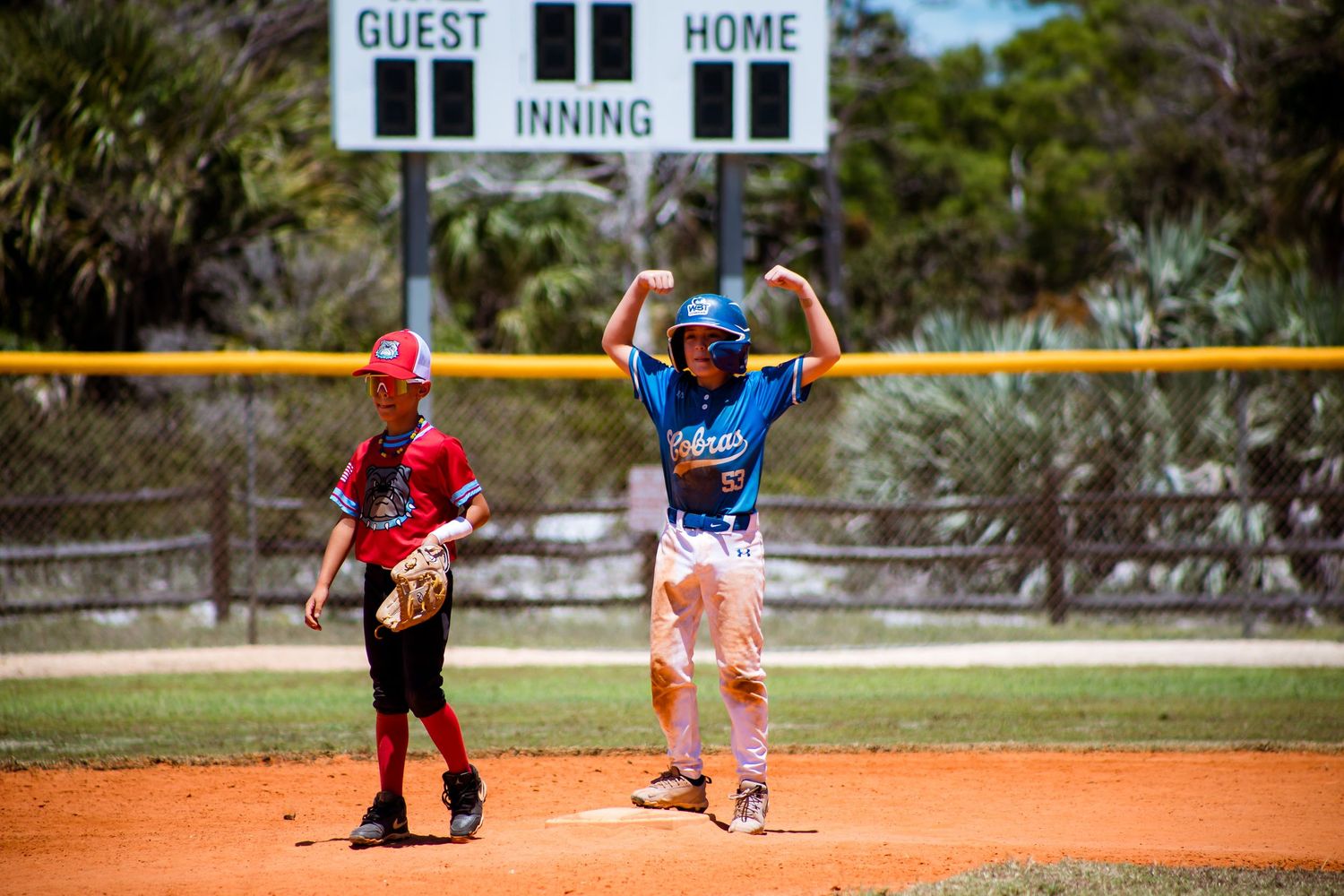 Two players on a baseball field with a scoreboard showing 11 innings in the background.