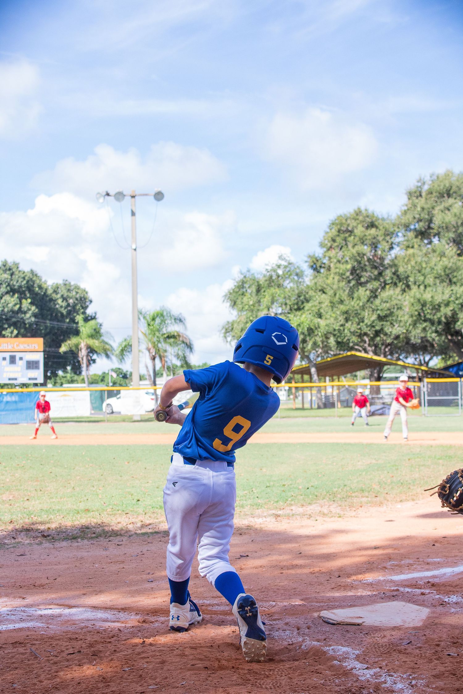 A baseball player in blue uniform follows through on their swing at home plate.