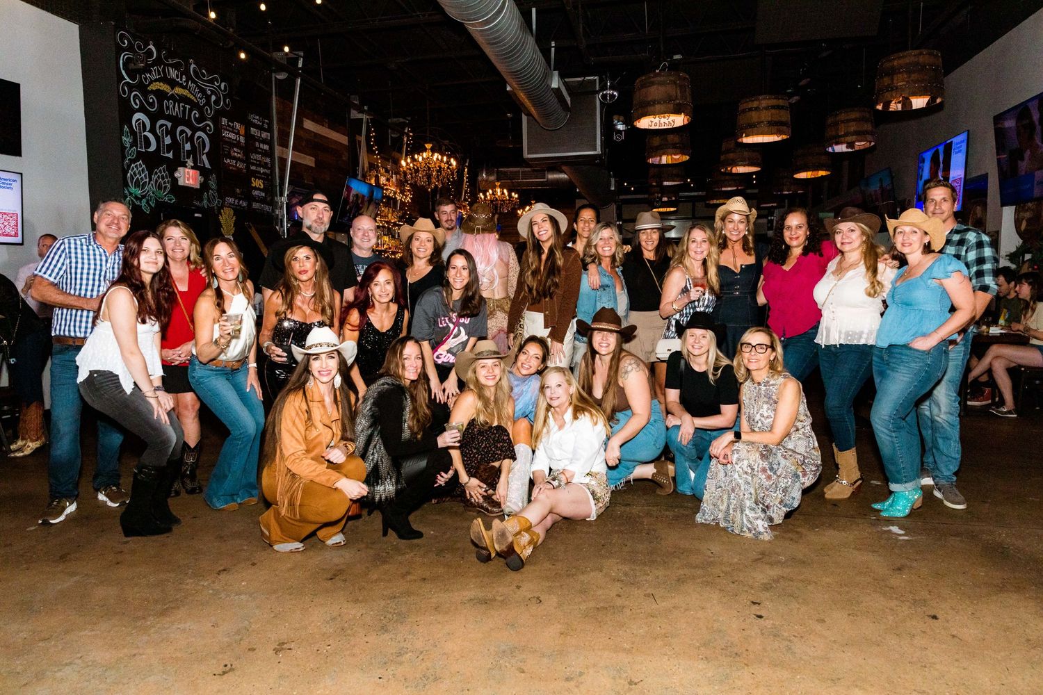 Large group photo of party guests posing together at casual indoor venue.