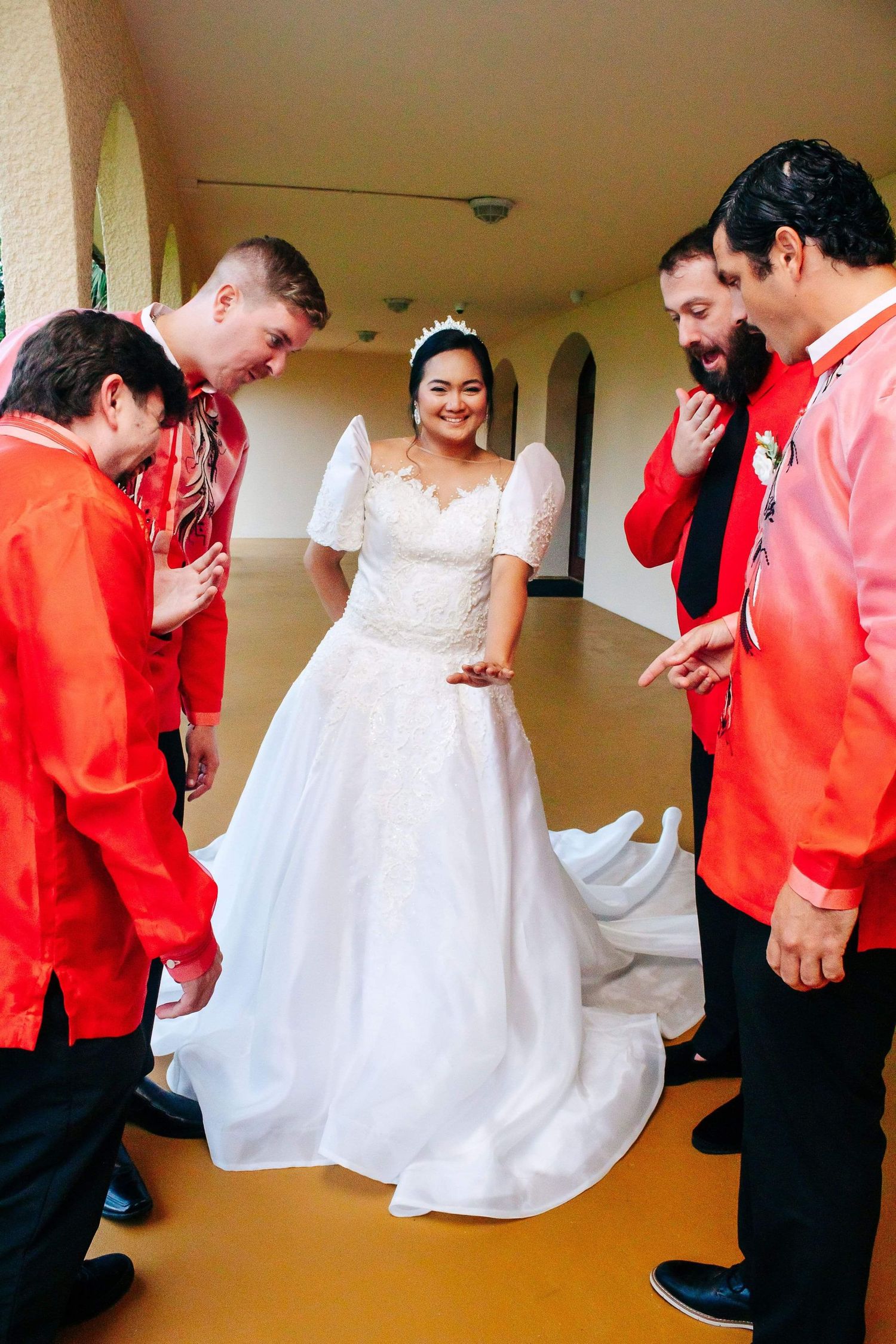 Wedding party performs choreographed dance with people in red shirts and white dresses in a hallway.