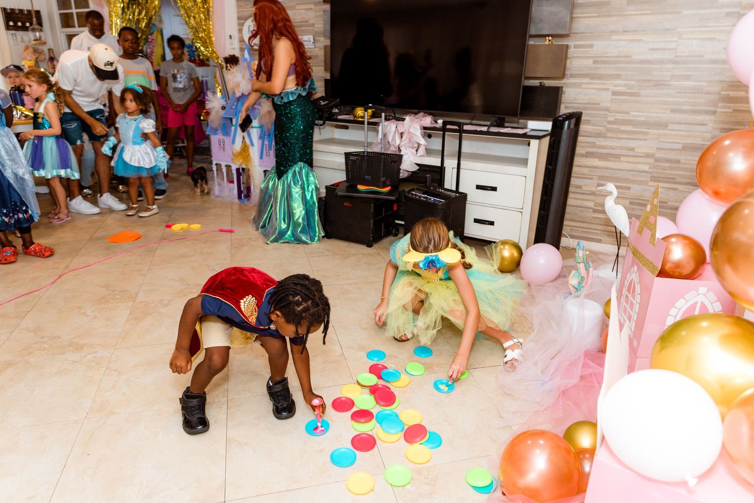 Children playing with colorful balloons on the floor at a themed birthday party.