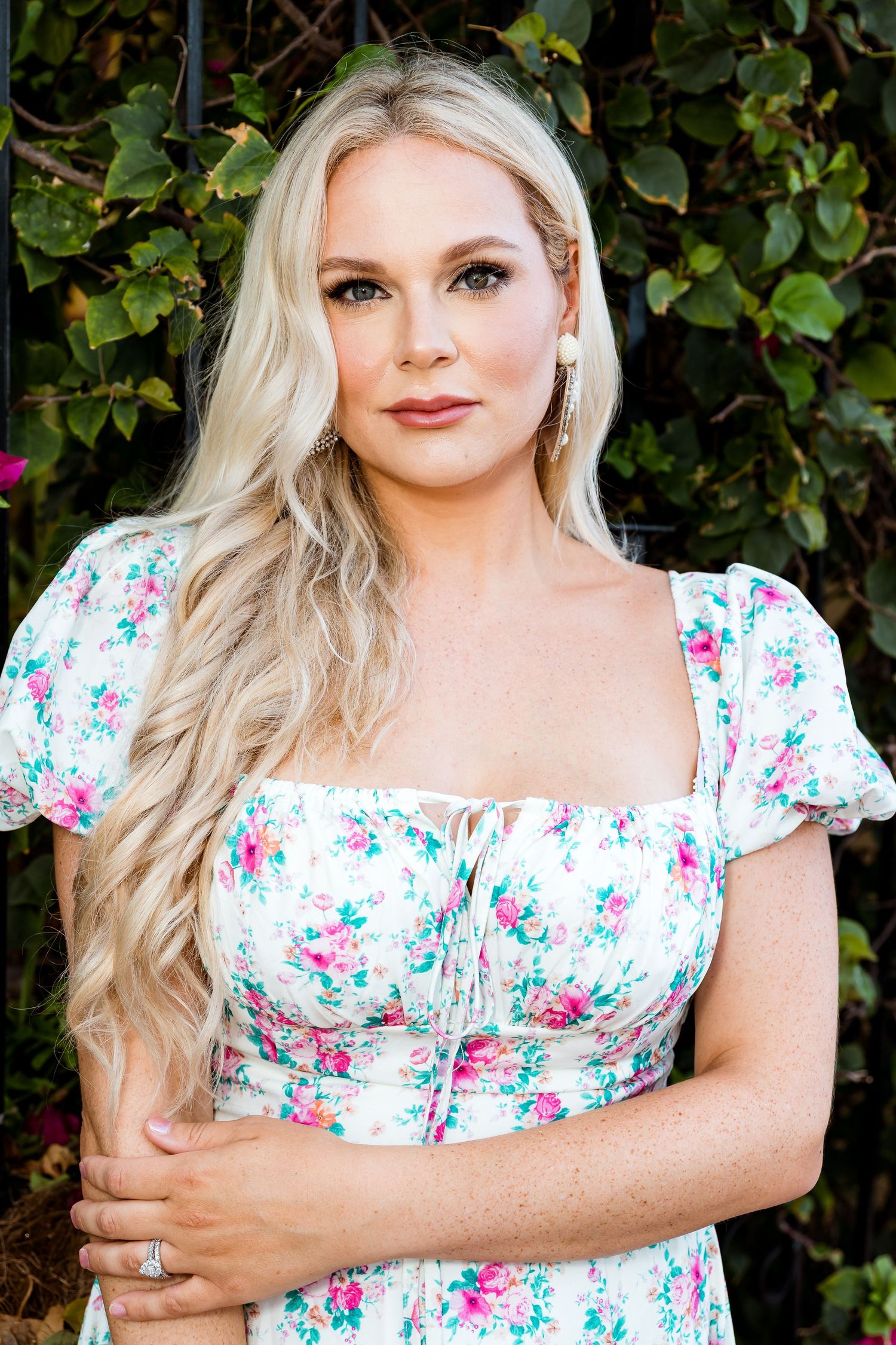 Feminine portrait with floral dress against green foliage background showing romantic spring style.