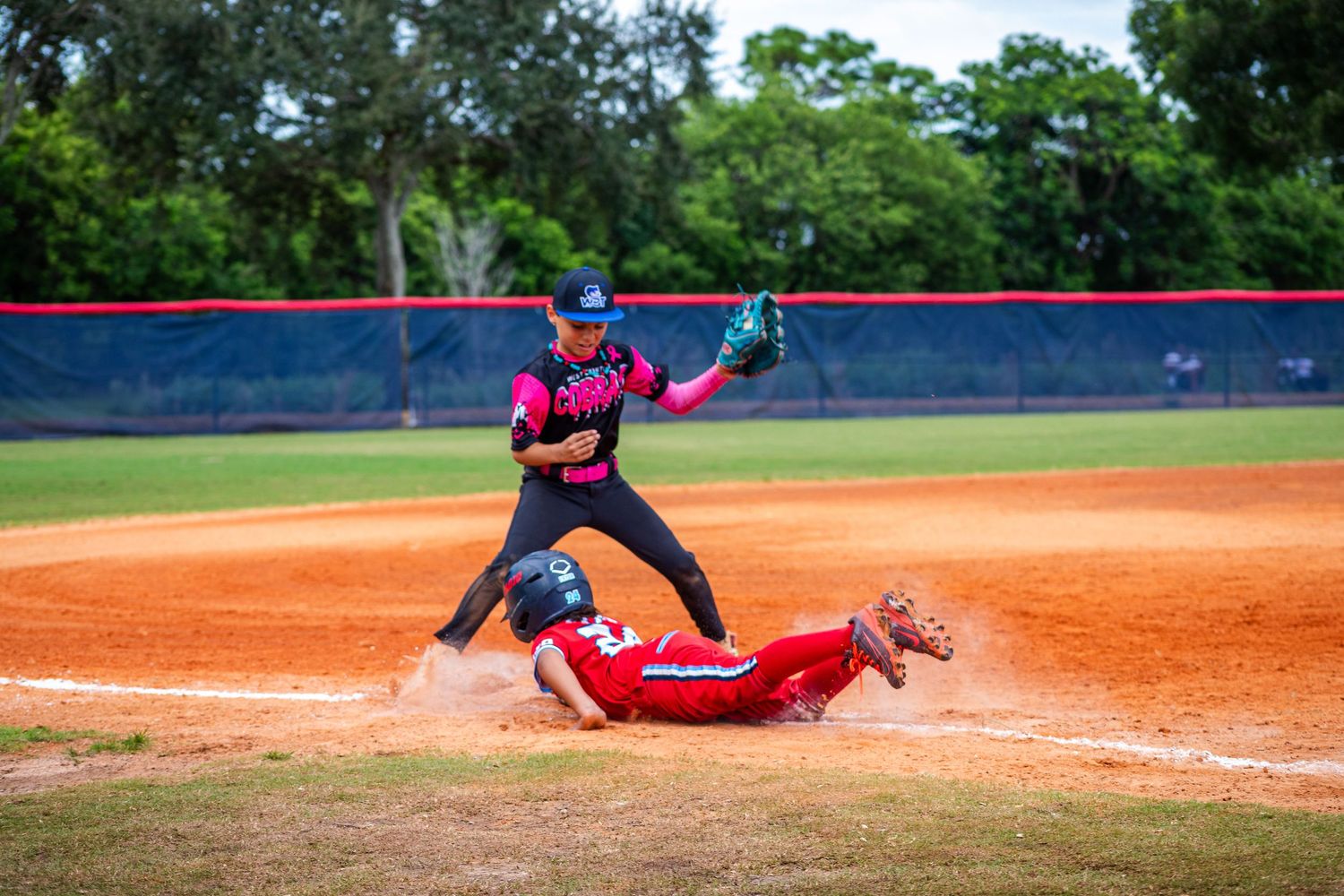 Baseball player executing a dramatic slide into base while opponent attempts to make the play.