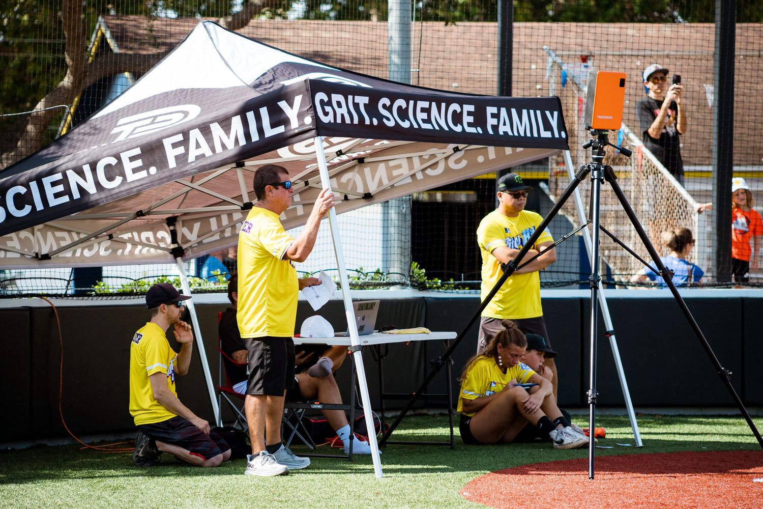 Crew members in yellow shirts set up equipment under a white tent at an outdoor science and family event.