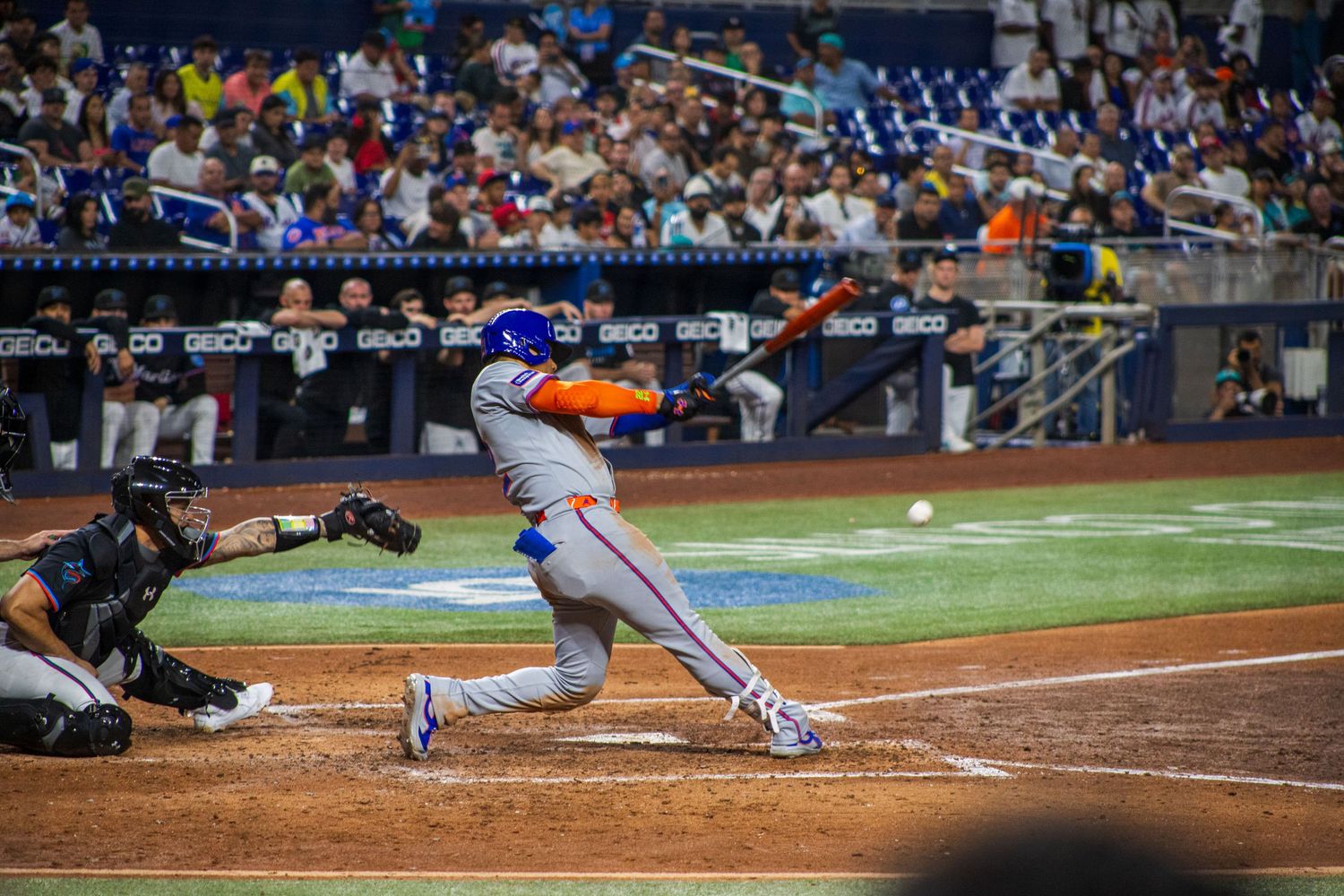 Baseball action sequence shows players in motion near home plate during professional game.