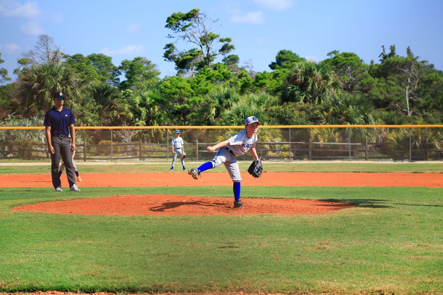 Pitcher in mid-delivery motion on baseball mound during daytime game.