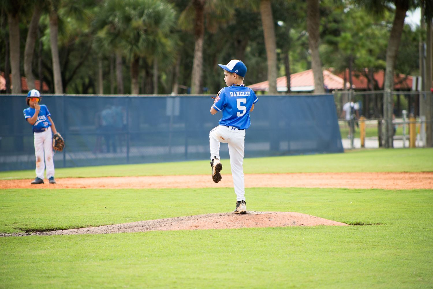 Baseball pitcher in blue jersey number 5 mid-delivery on the mound during a game.