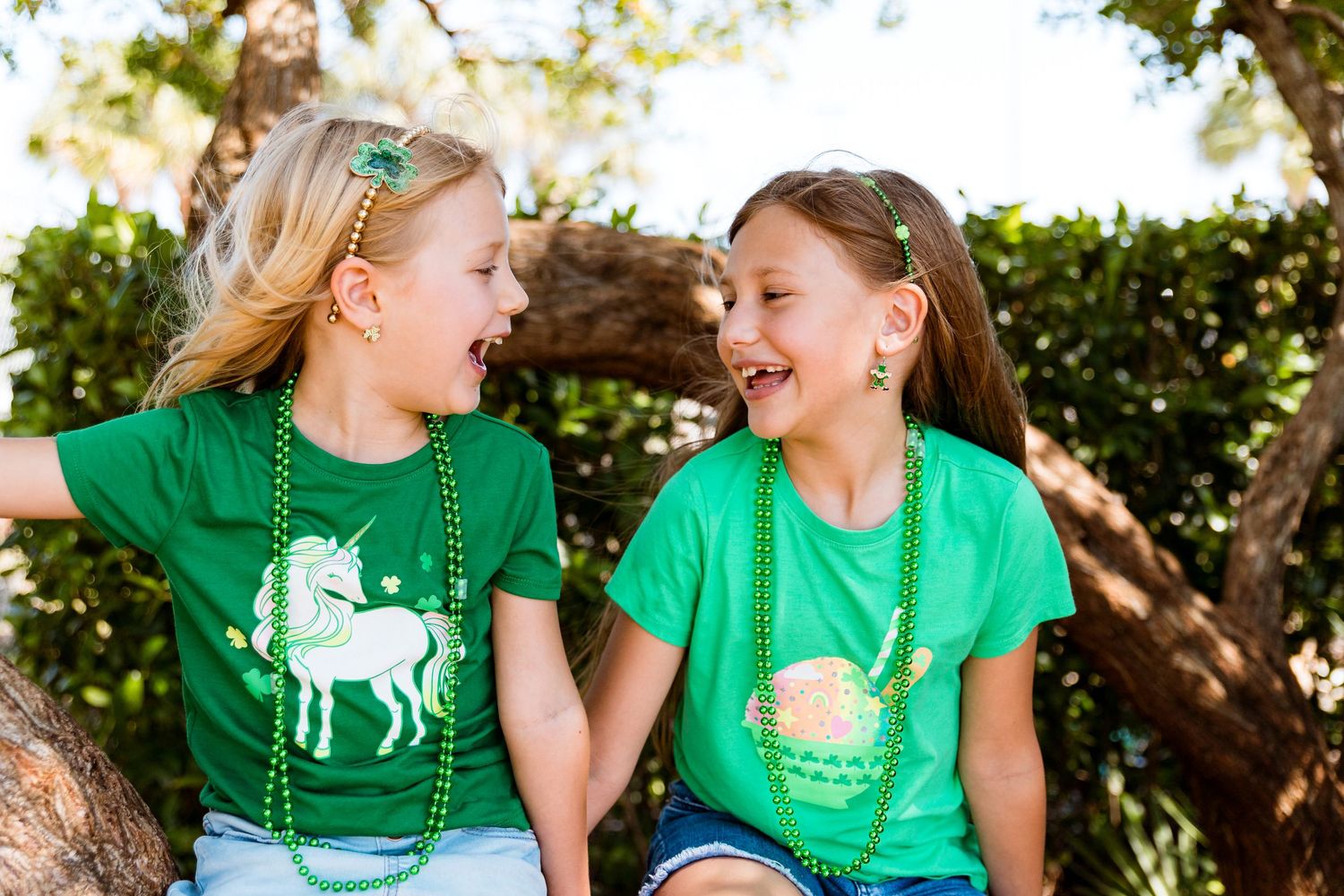 Children in green unicorn t-shirts sharing a laugh together outdoors.