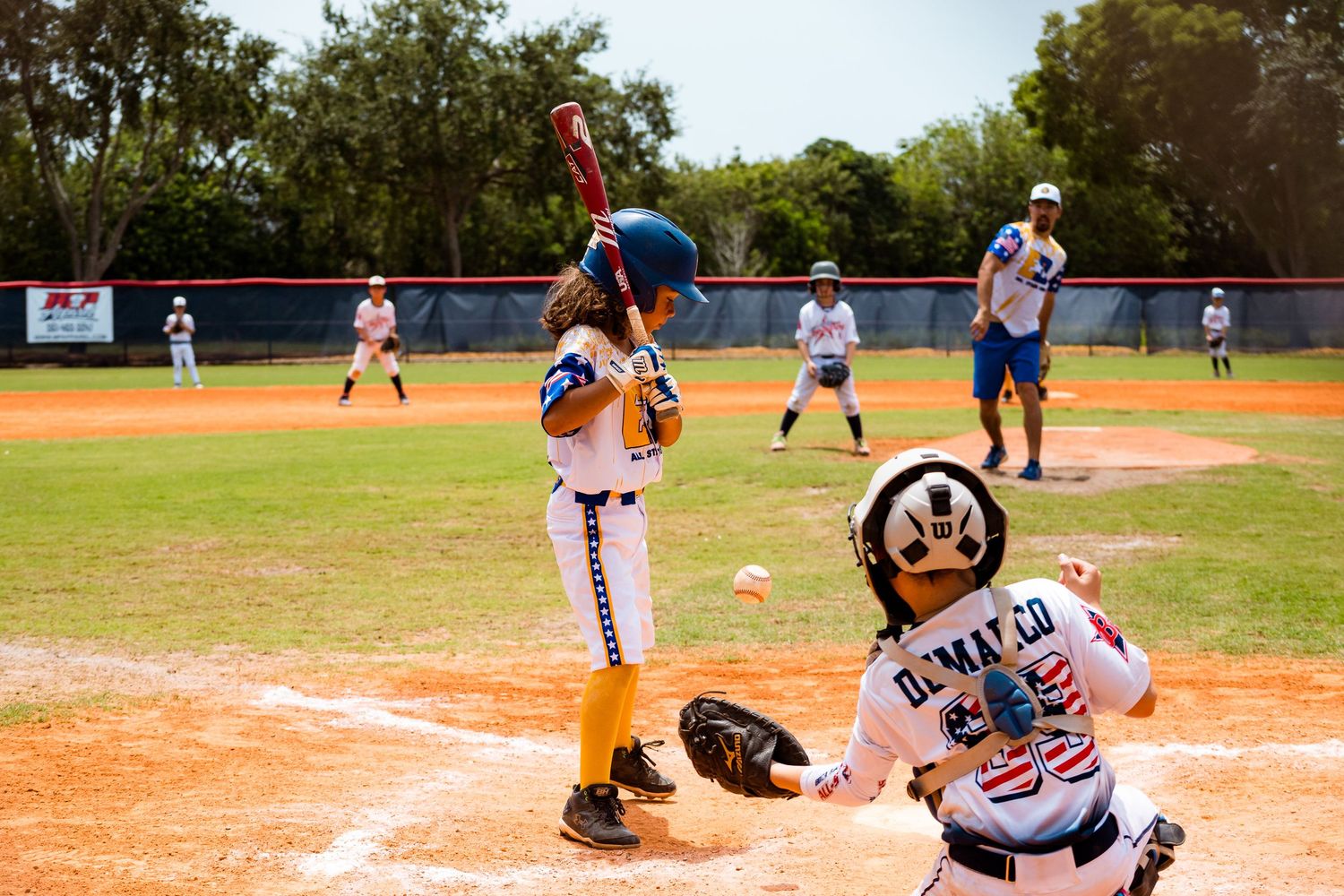 Baseball players in action during a game with one sliding into home plate while the catcher waits for the throw.
