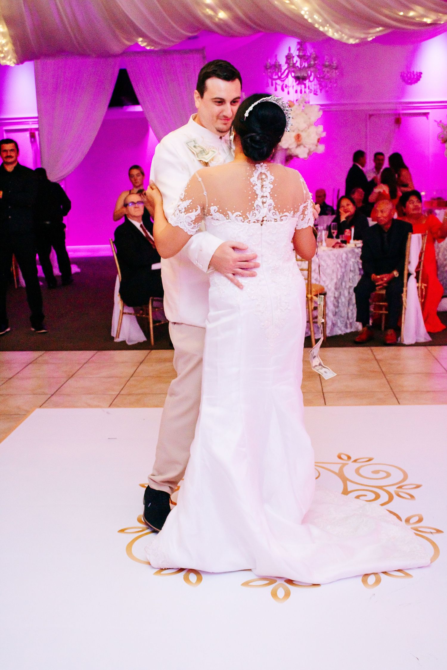 Wedding couple dancing on decorated white dance floor with purple ambient lighting.