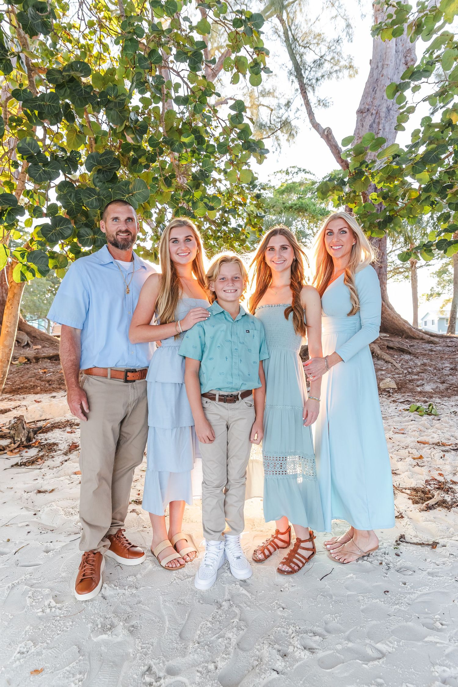 Family portrait session on beach showing feet and legs in coordinated blue and beige outfits.