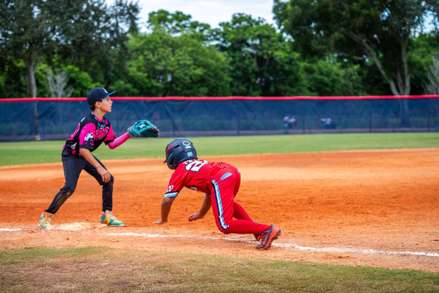 Baseball player slides into base while opponent reaches to make the tag during game play.