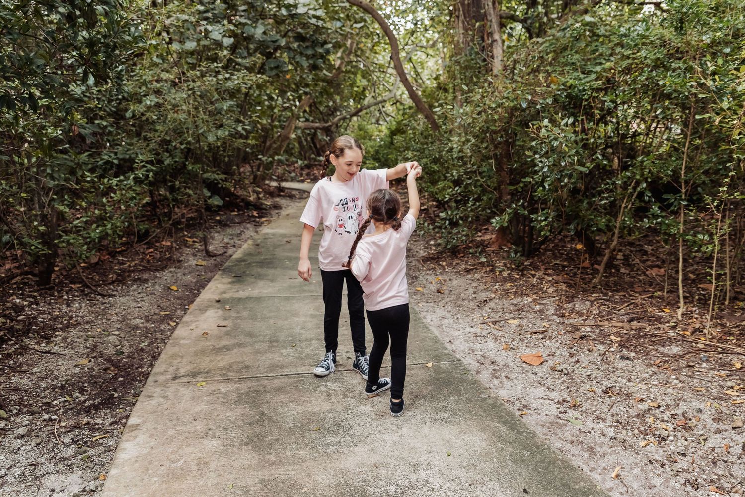 A couple walks along a wooded path in a forest setting during a romantic photo session.