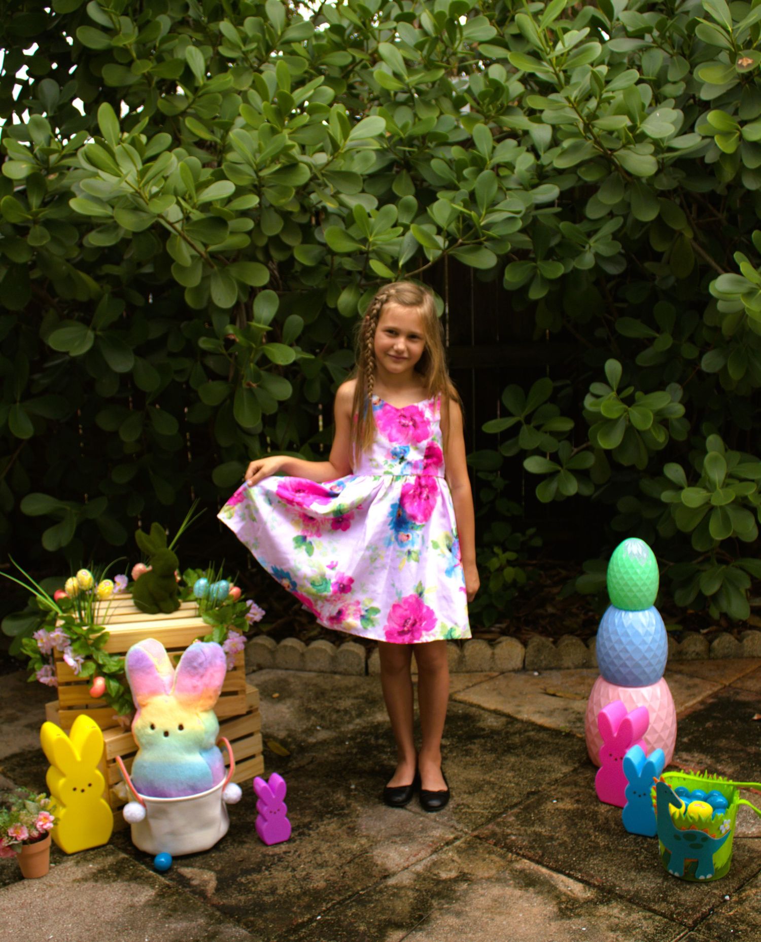 Festive Easter display with colorful decorations and bunny figures against green foliage.