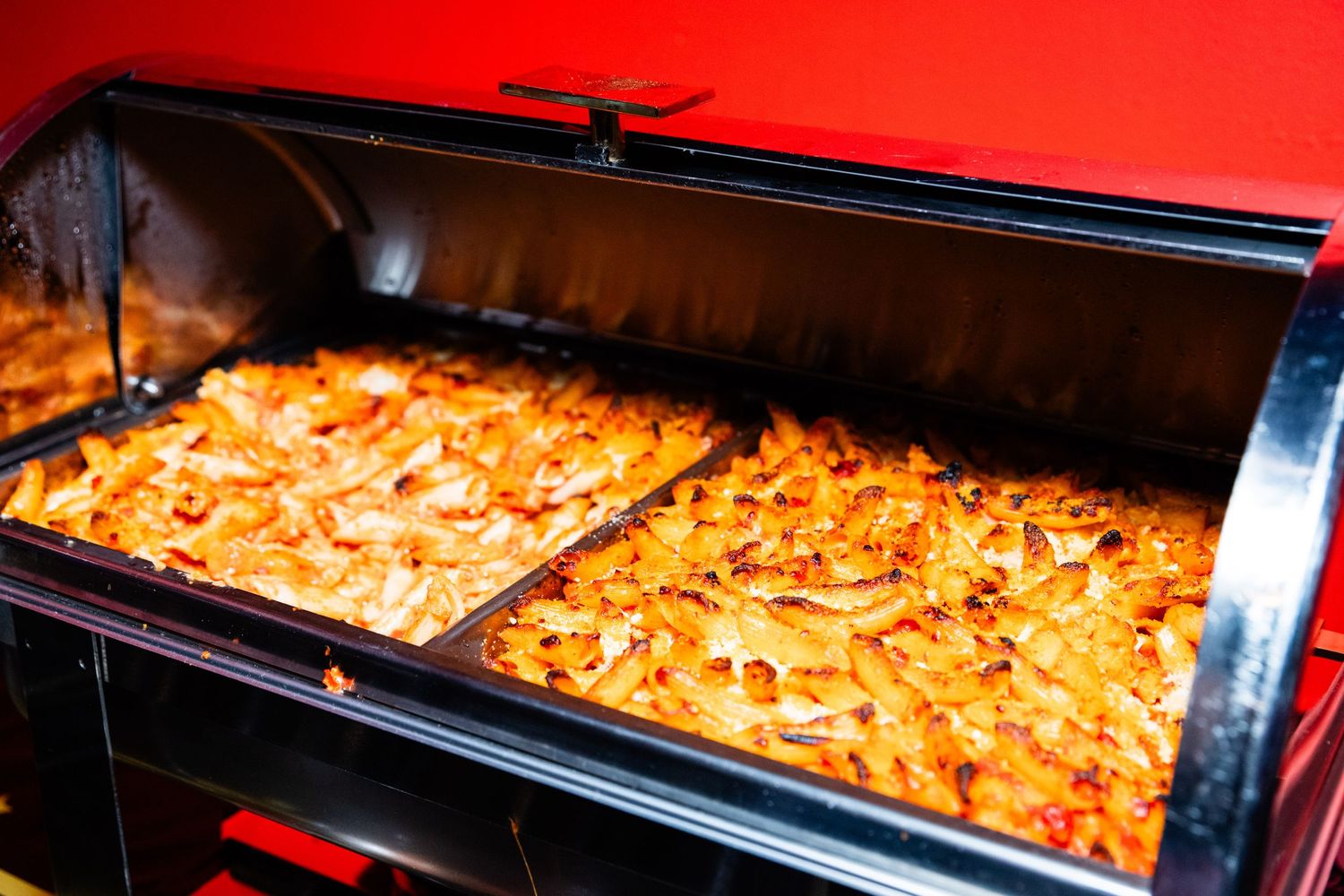 An image of a baking tray filled with golden brown baked goods in a red oven.