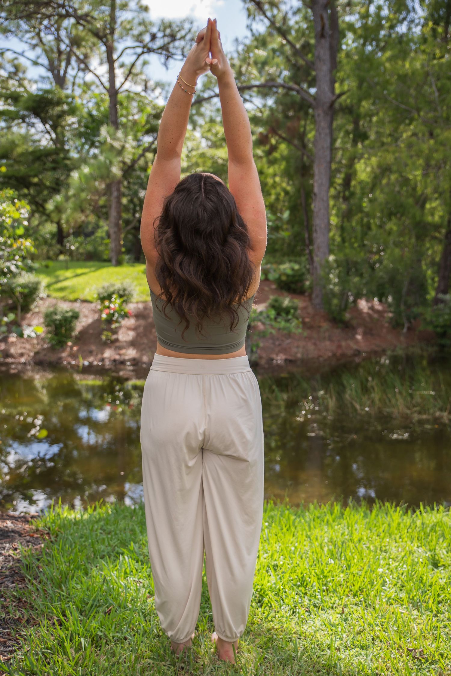 A series of photographs showing someone practicing outdoor yoga poses in loose white pants near a serene lake.