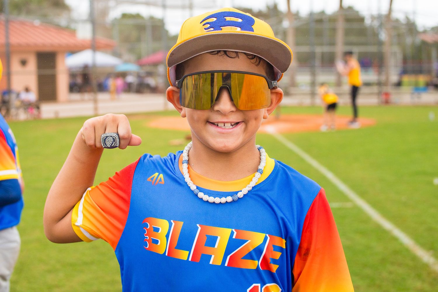 Young athlete in Blaze uniform shows excitement while wearing orange mirrored sunglasses.