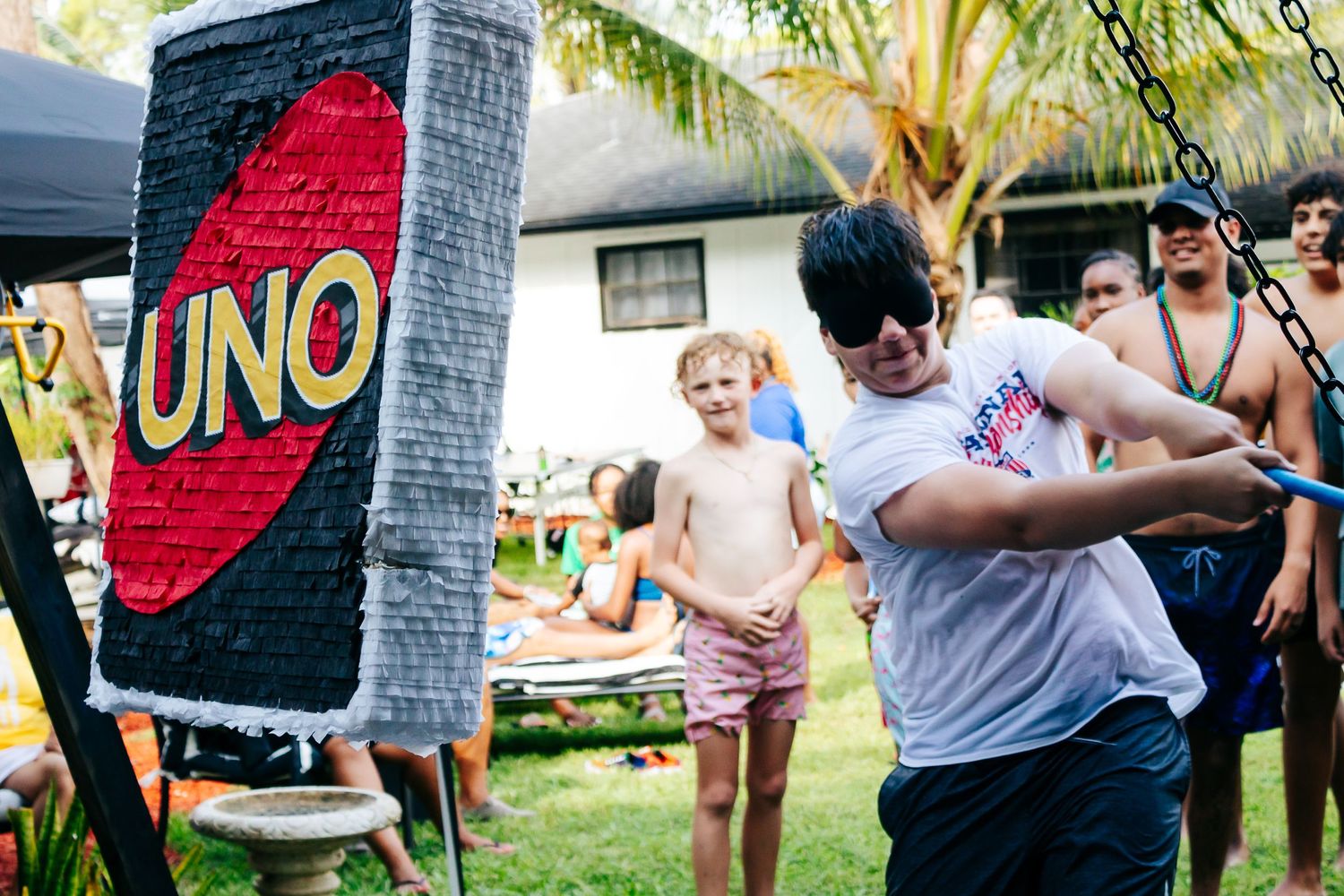 People playing with a giant UNO card game setup in a backyard.