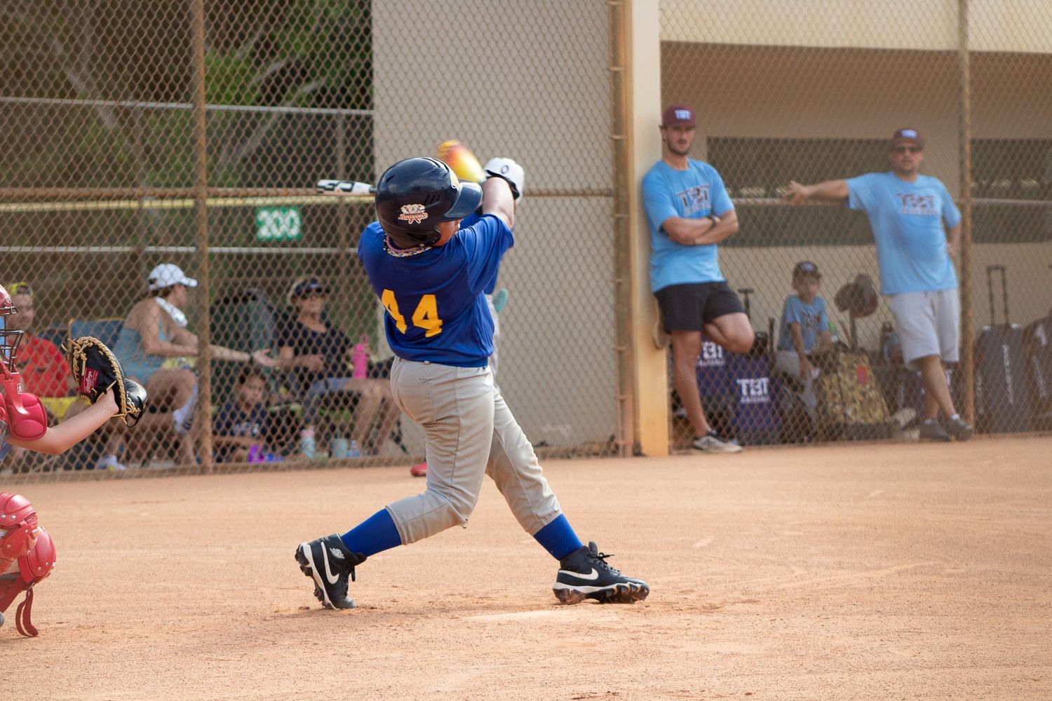 Baseball player in blue uniform swinging bat during game on dirt field.