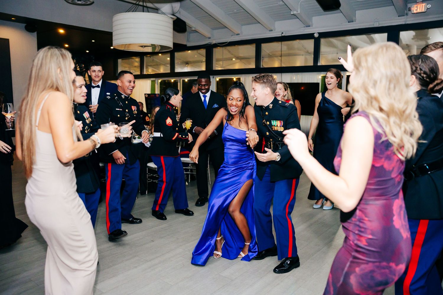 People dancing and socializing at a formal military ball with Marines in dress blues uniforms.
