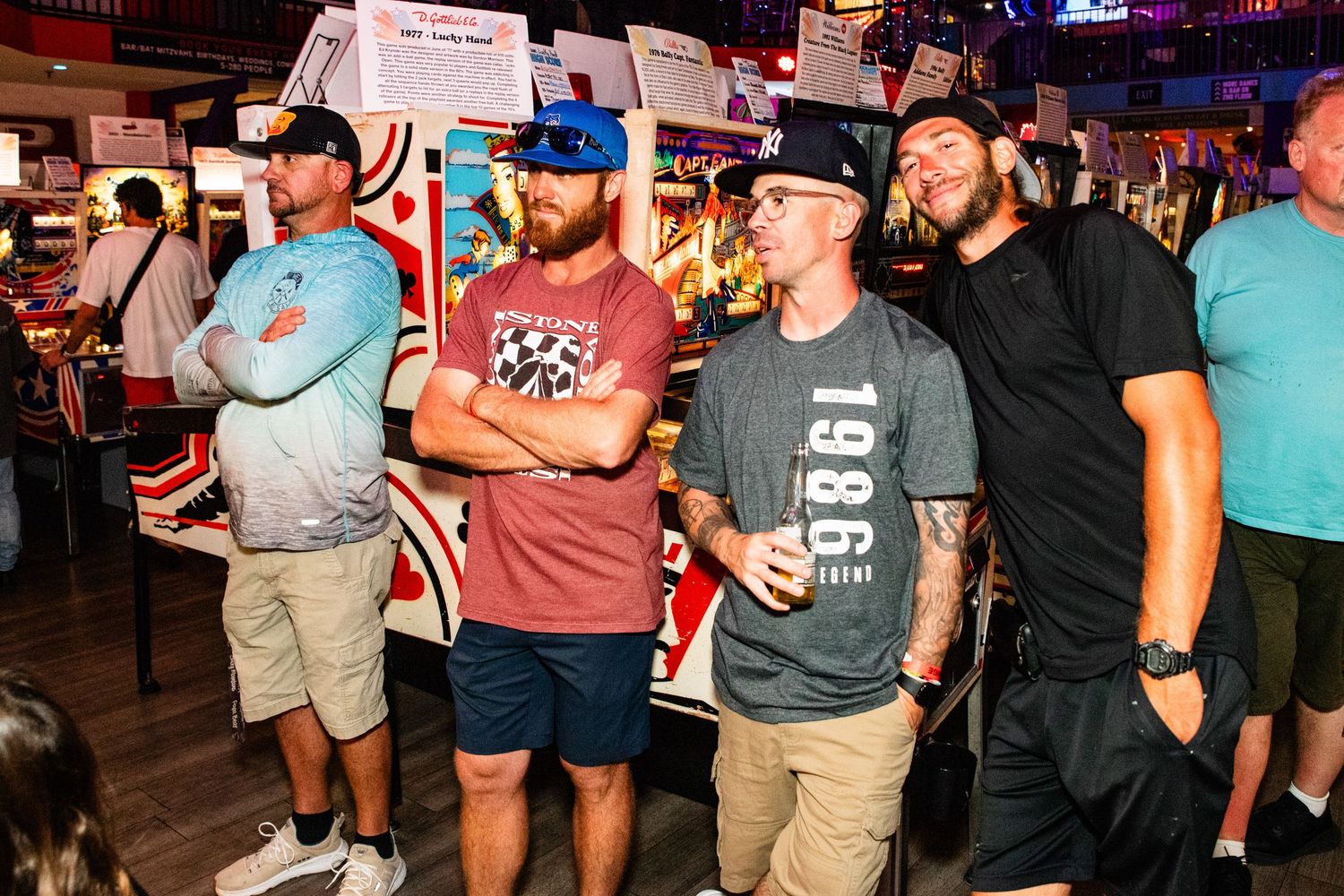 The image shows a group of people standing together in what appears to be a bar or entertainment venue.