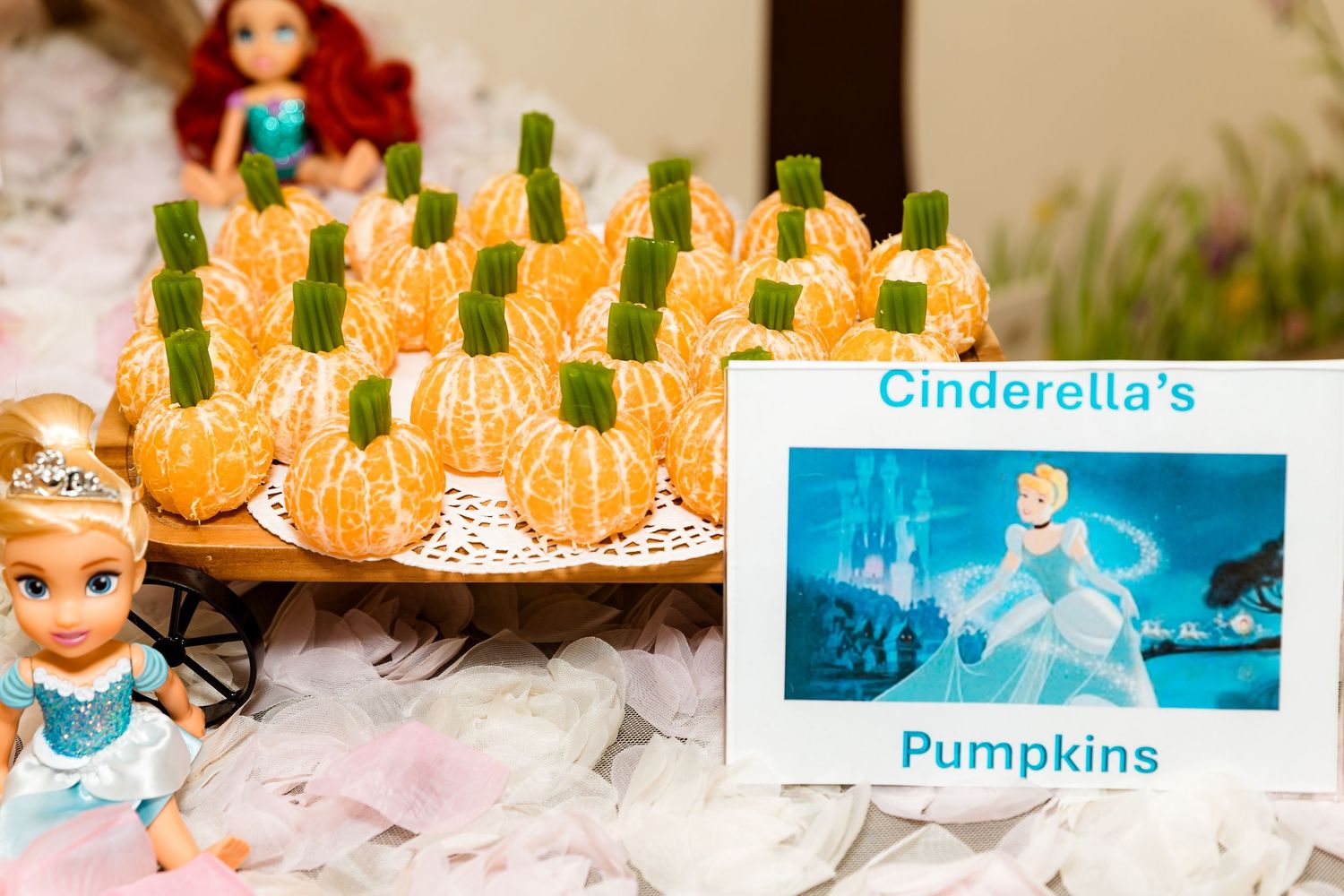 Decorative pumpkins arranged with Disney-themed party elements on a table with white decor.