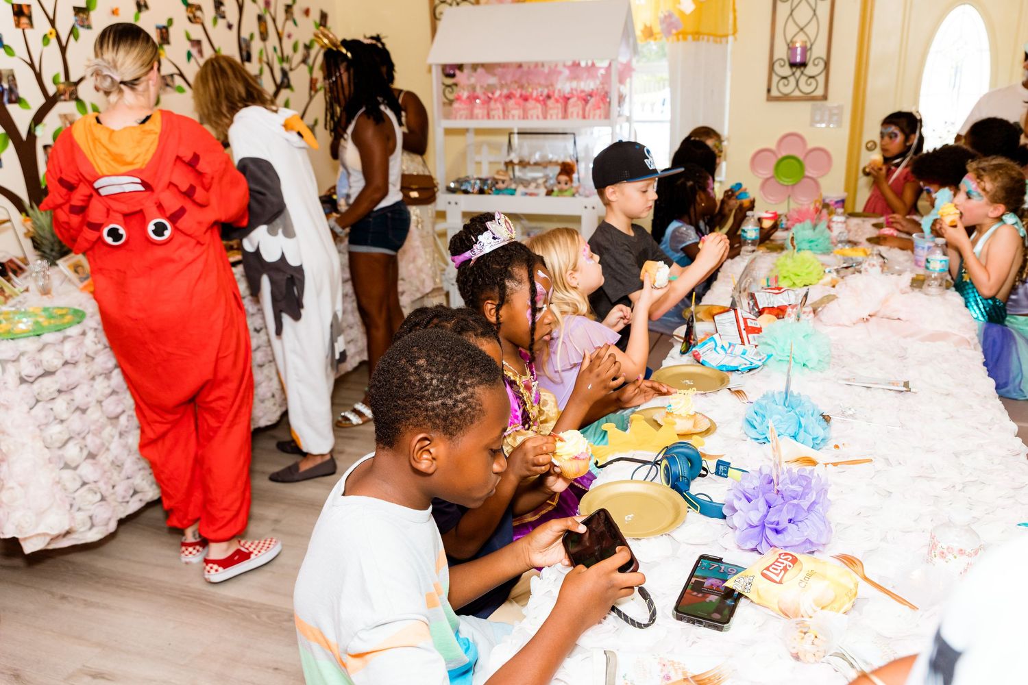 Children engaged in crafting activities at a long table during a themed party celebration.
