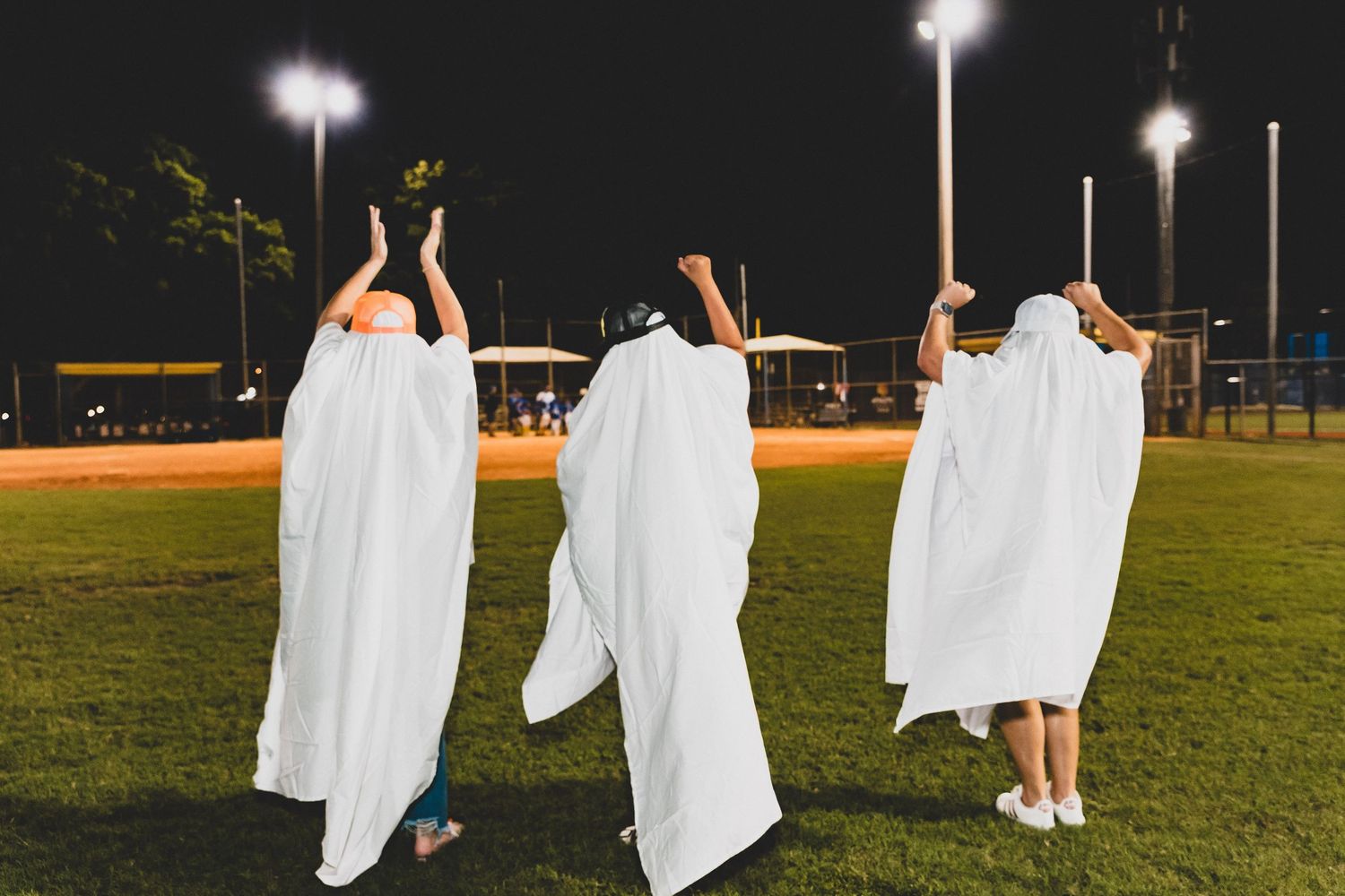 White-sheeted figures spread out across a dark grass field under stadium lights.