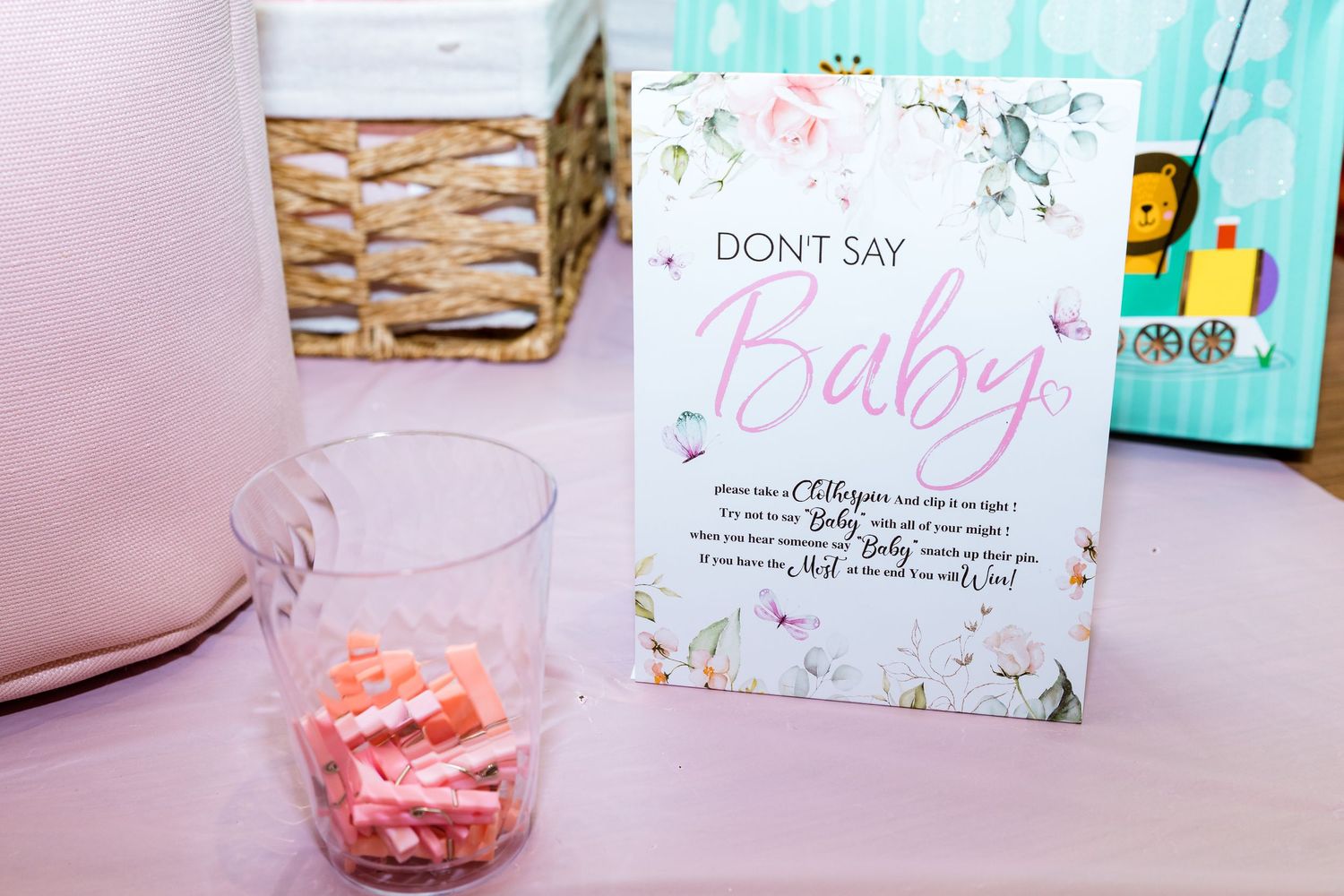 Delicate pink and mint green baby shower decorations with floral signage on display.