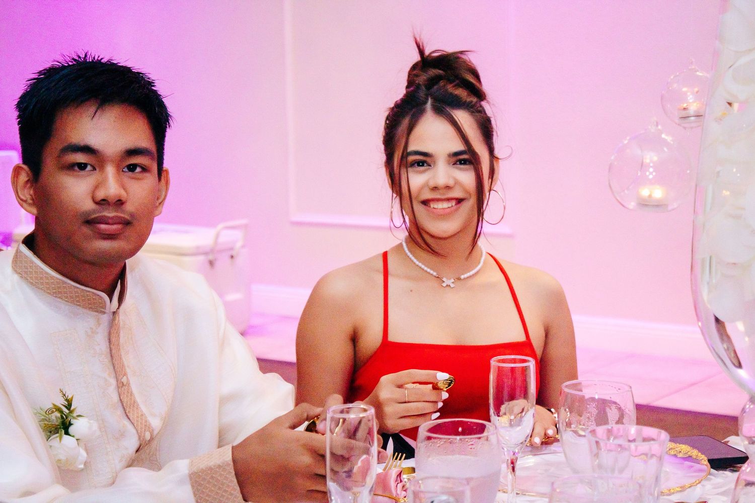 Wedding reception dinner with pink mood lighting and table decor.