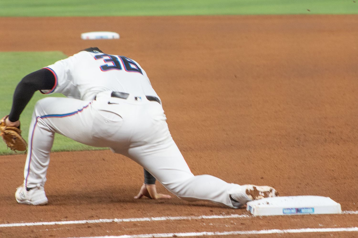Baseball player stretches to cover first base during defensive play.