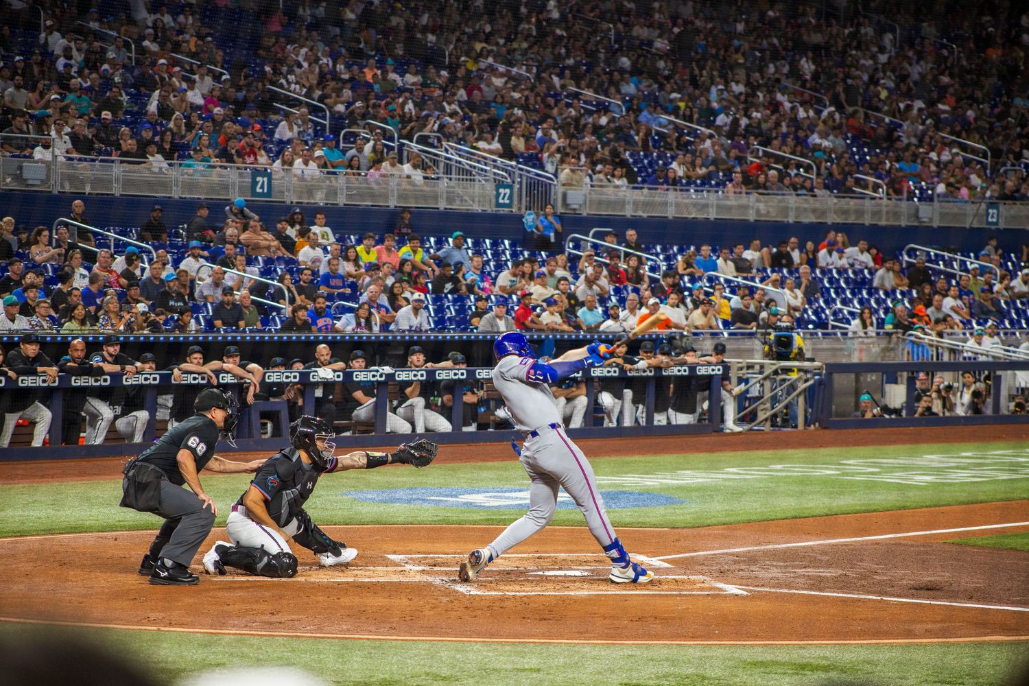 Baseball player slides into home plate as the catcher awaits the throw during an evening game.