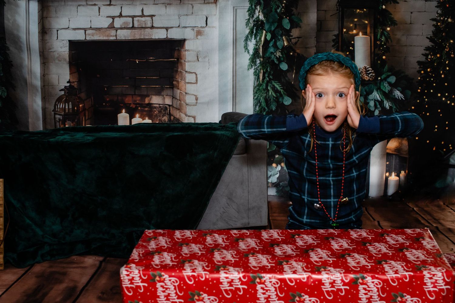 A surprised expression as someone peeks over wrapped Christmas presents by a decorated fireplace.