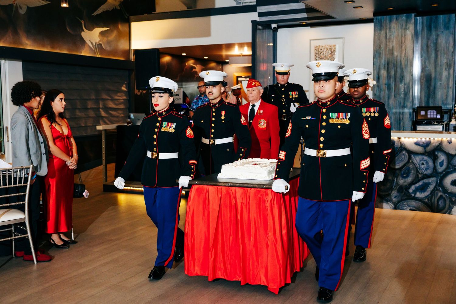 Military service members and guests gather around tables at a formal dining event.