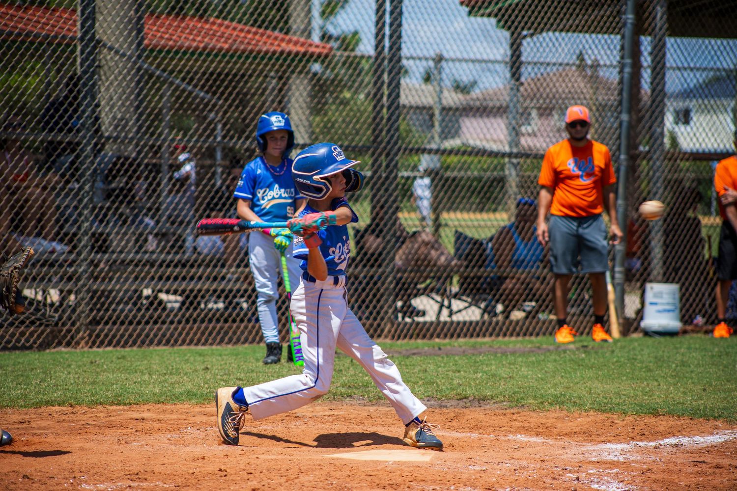 A baseball player in blue uniform swings at a pitch during a game on a sunny day at the ballpark.