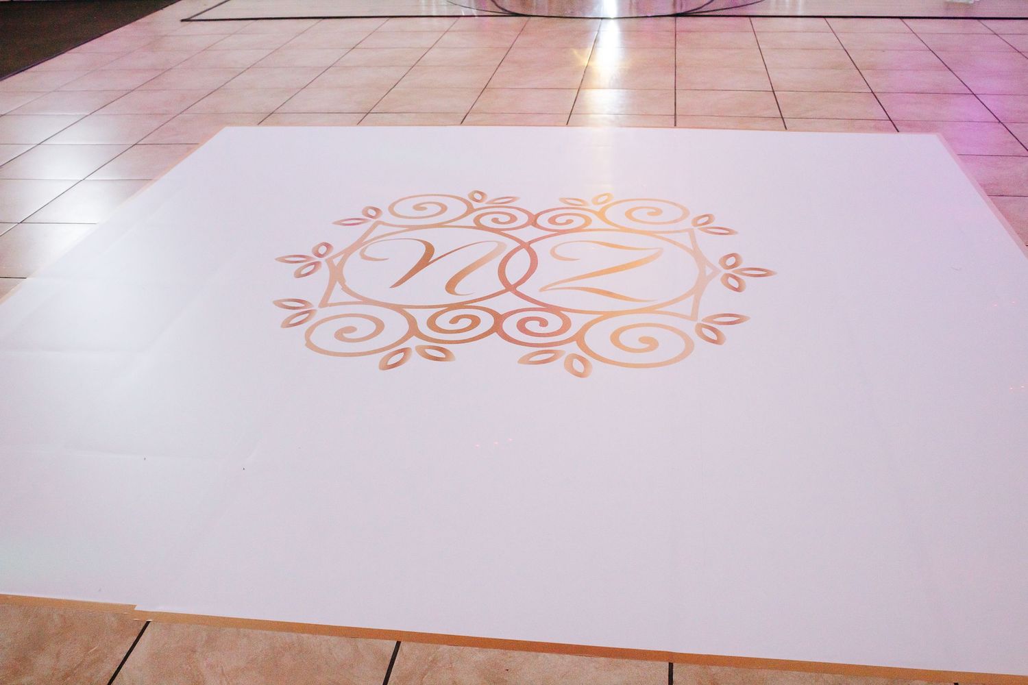 White dance floor with ornate gold scroll design pattern.