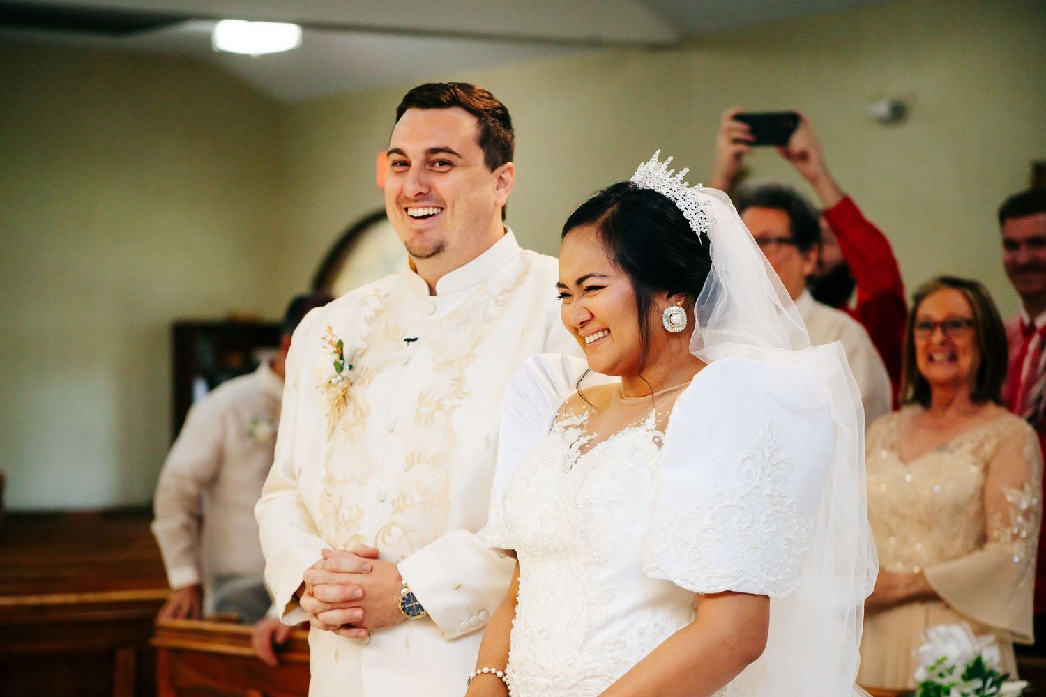 A happy newlywed couple smiling together during their wedding ceremony in a church.