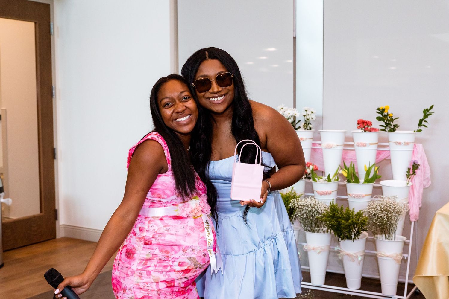 Party guests mingling at a pink-themed celebration with balloon decorations.
